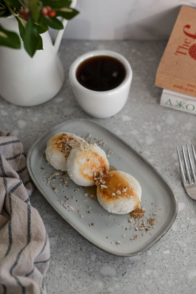 Сырники с орехами и соусом, рядом чёрный кофе